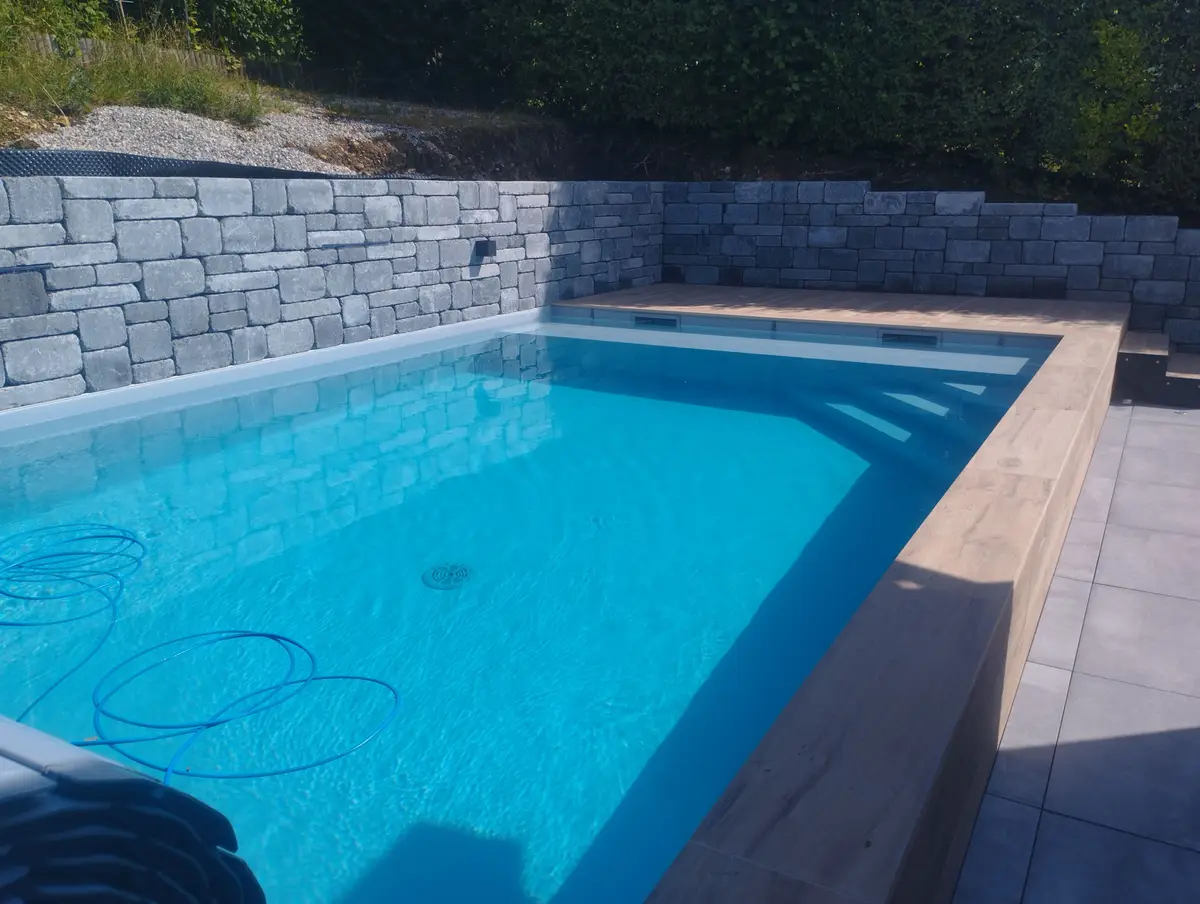 Piscine avec enrochement en pierre et terrasse bois
