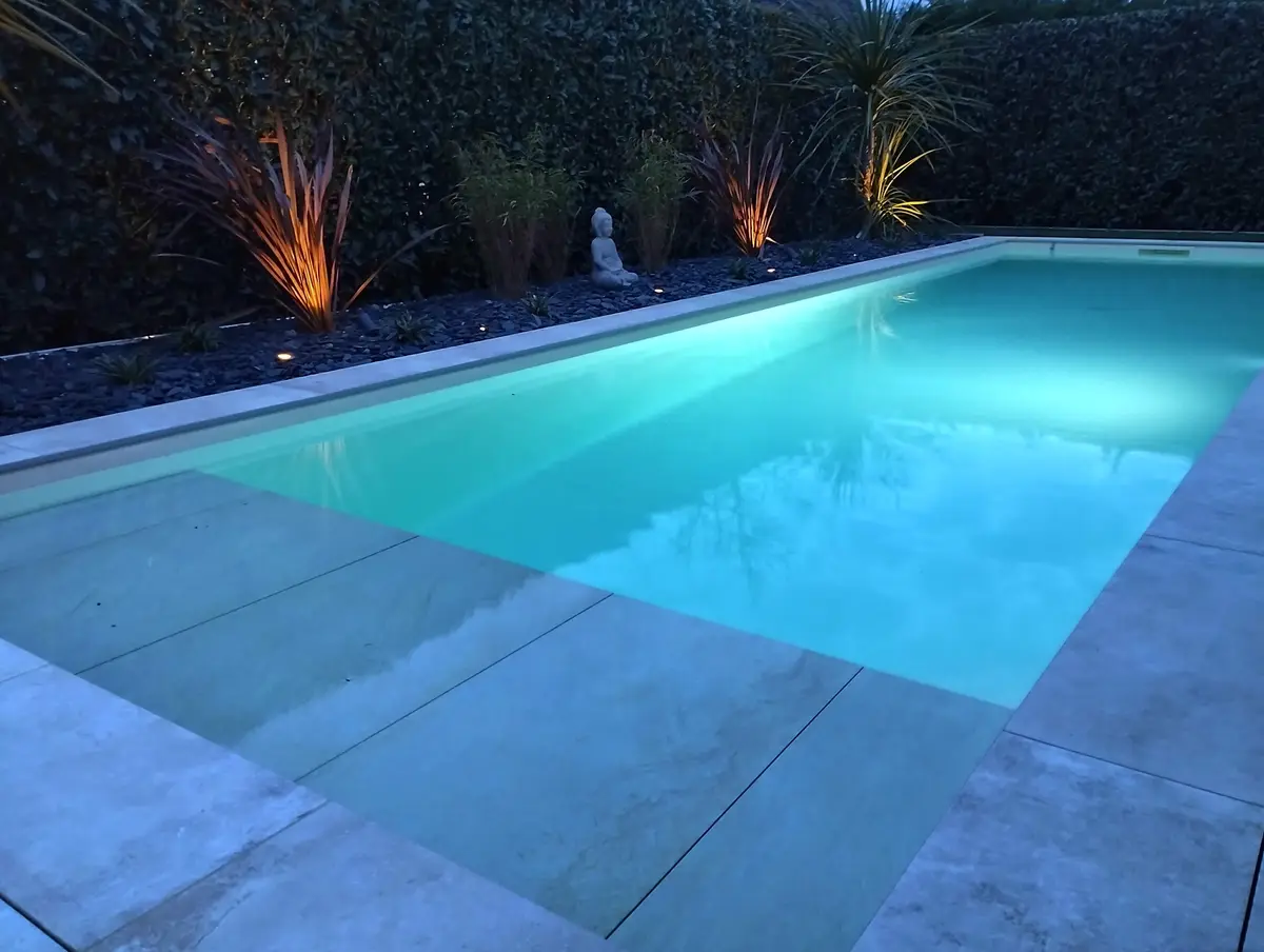 Piscine paysagee avec palmiers et eclairage au crepuscule