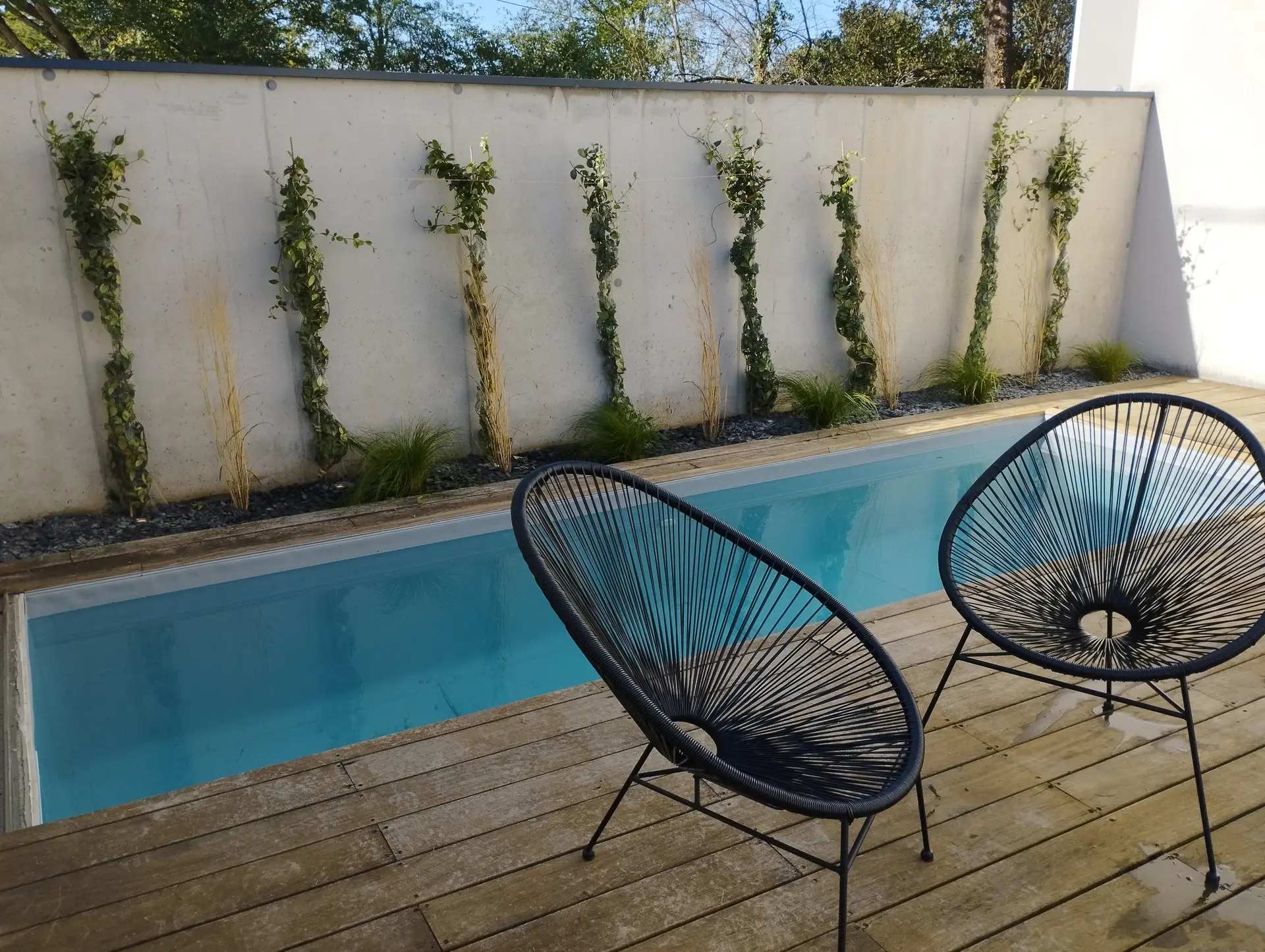 Belle piscine maconnee ensoleillee avec terrasse bois, realisee par EV2M